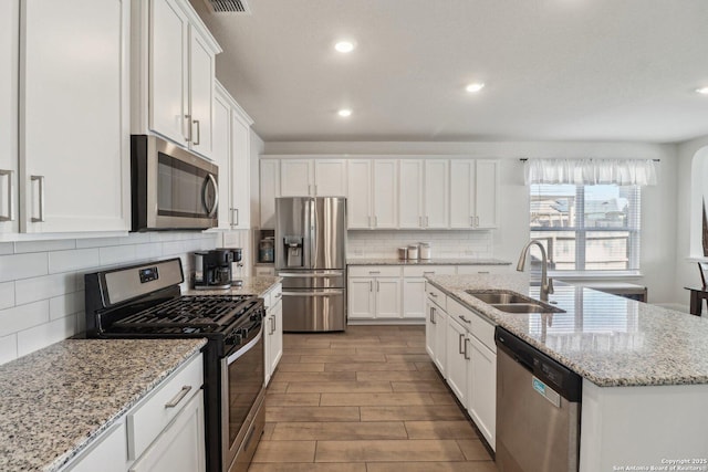 kitchen featuring a sink, appliances with stainless steel finishes, white cabinets, and wood tiled floor