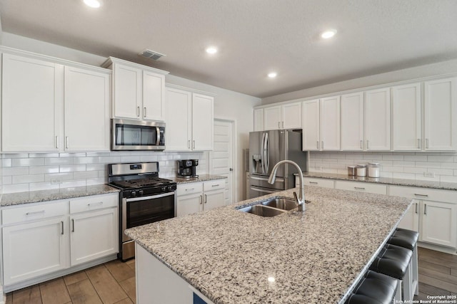 kitchen featuring a sink, visible vents, appliances with stainless steel finishes, and wood finished floors