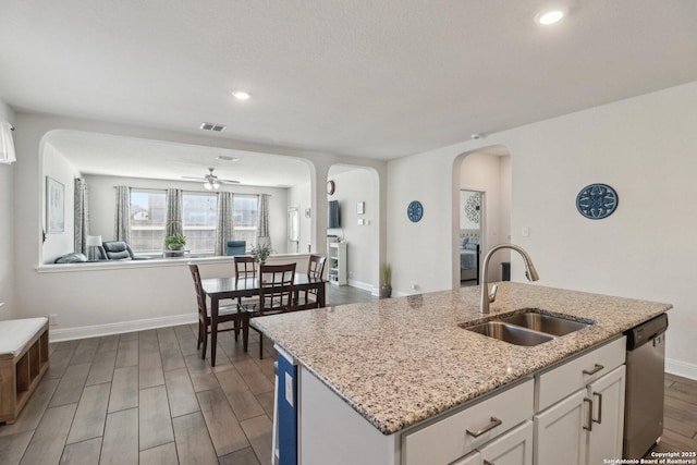 kitchen with visible vents, open floor plan, dishwasher, arched walkways, and a sink