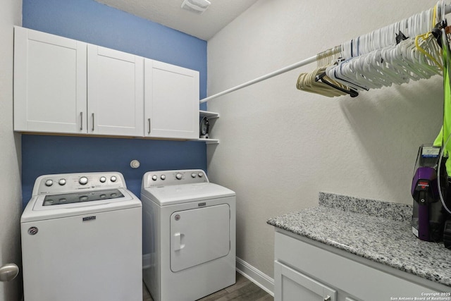 washroom featuring wood finished floors, visible vents, baseboards, separate washer and dryer, and cabinet space