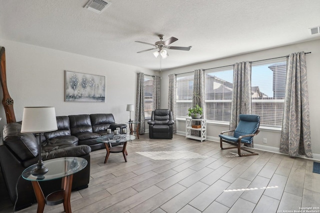 living area featuring wood finished floors, baseboards, visible vents, ceiling fan, and a textured ceiling