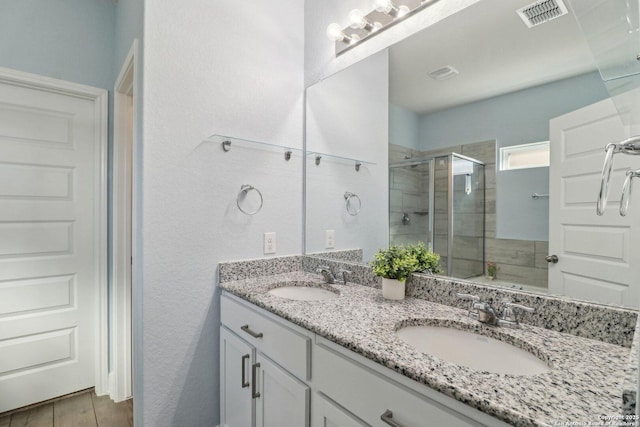 full bath with double vanity, a stall shower, visible vents, and a sink