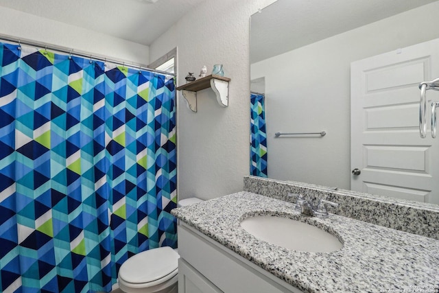 full bath featuring toilet, vanity, a shower with curtain, and a textured wall