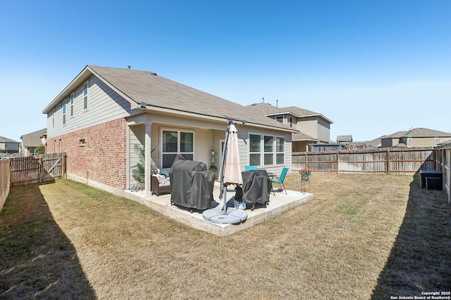 back of house with a patio, a yard, a fenced backyard, and brick siding