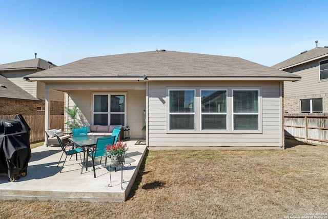 back of property featuring fence, a yard, a shingled roof, a patio area, and an outdoor hangout area