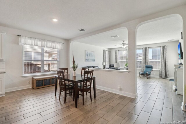 dining room with radiator, a ceiling fan, visible vents, light wood-style flooring, and arched walkways