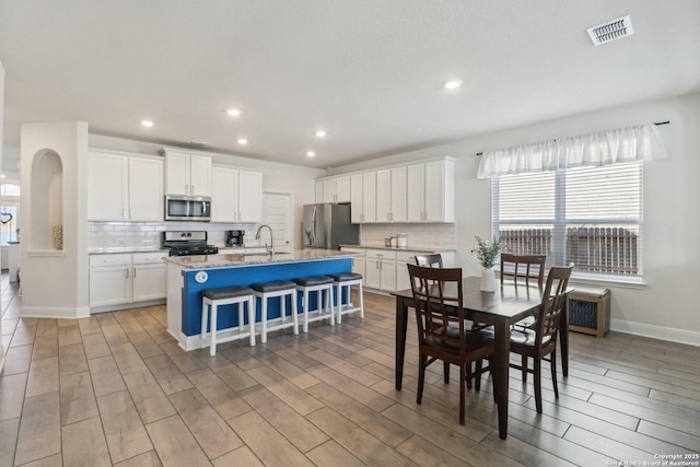 dining space featuring visible vents, baseboards, recessed lighting, arched walkways, and light wood-style floors