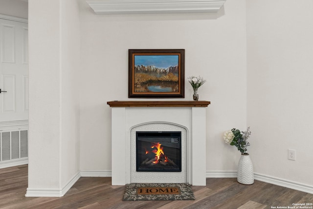 interior details with visible vents, baseboards, a fireplace with flush hearth, and wood finished floors