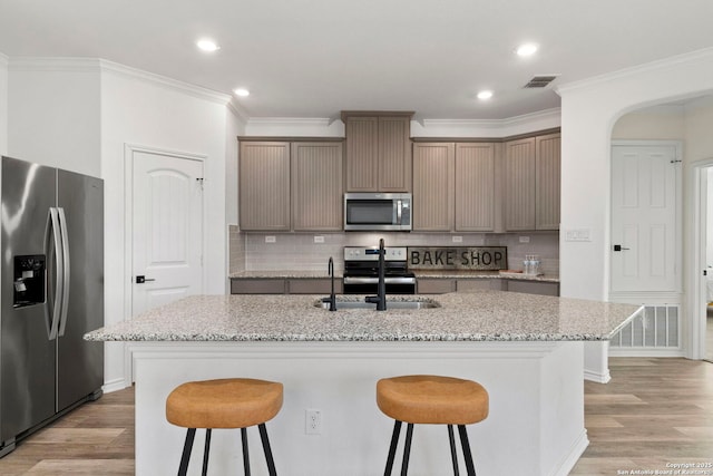 kitchen with visible vents, decorative backsplash, appliances with stainless steel finishes, a kitchen breakfast bar, and light wood-type flooring