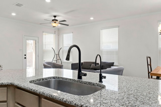 kitchen featuring crown molding, light stone countertops, visible vents, and a sink