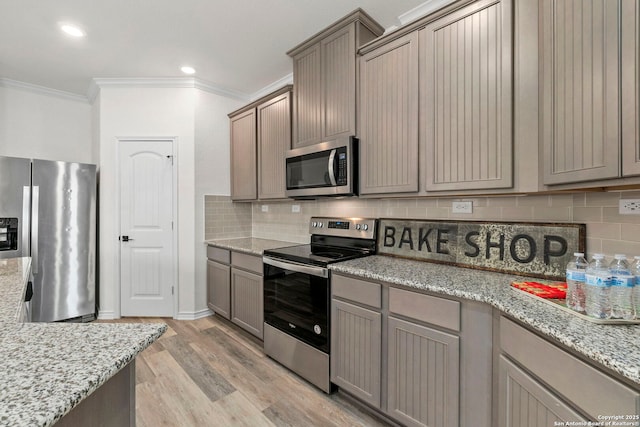 kitchen featuring crown molding, light wood-style floors, tasteful backsplash, and stainless steel appliances