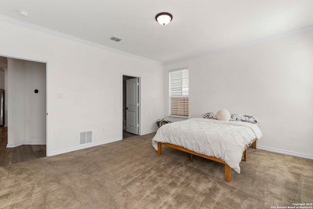 carpeted bedroom featuring visible vents, baseboards, and ornamental molding