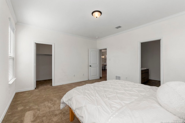 carpeted bedroom featuring visible vents, baseboards, a spacious closet, and crown molding