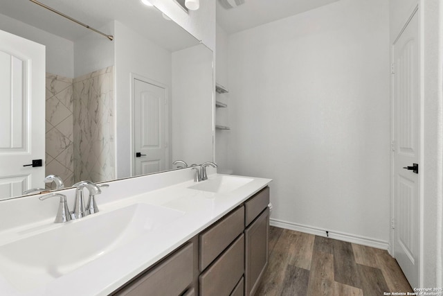 full bathroom with a sink, baseboards, wood finished floors, and double vanity