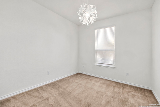 unfurnished room with baseboards, carpet, and an inviting chandelier