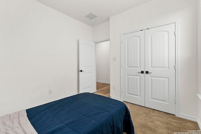 bedroom featuring carpet, visible vents, a closet, and baseboards