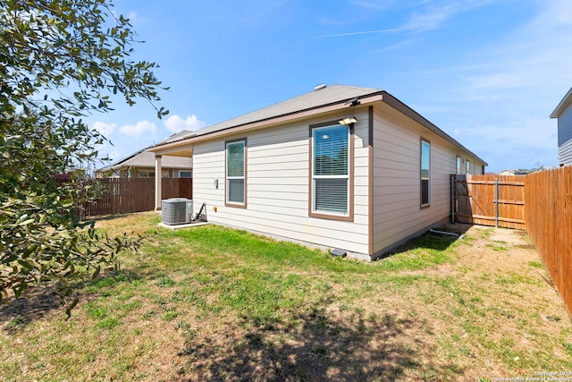 back of house with a yard, central AC, and a fenced backyard