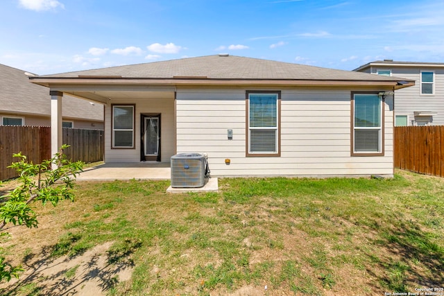 rear view of property featuring a patio area, central AC unit, a lawn, and a fenced backyard