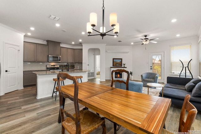 dining space with crown molding, recessed lighting, wood finished floors, and arched walkways