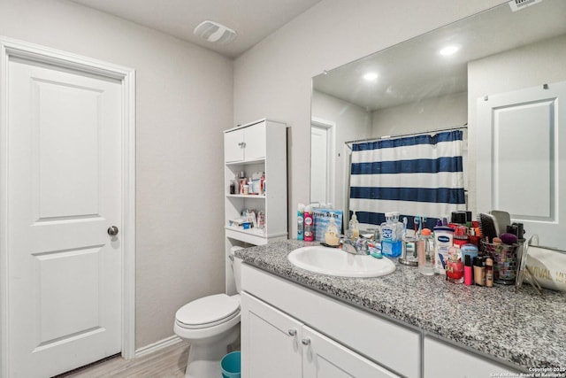 full bathroom with visible vents, toilet, vanity, and wood finished floors