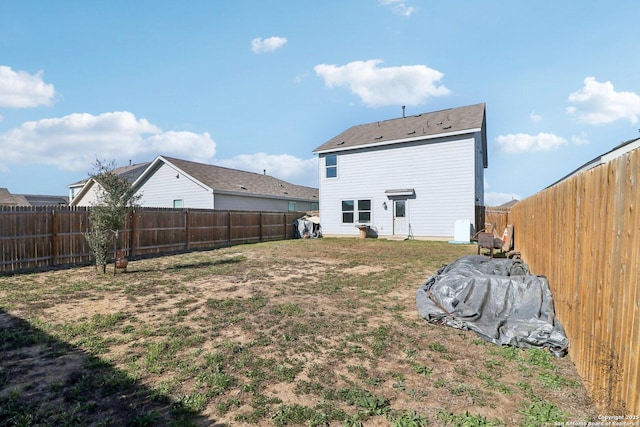 back of house with a yard and a fenced backyard