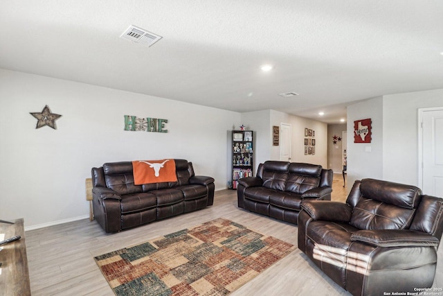 living room featuring baseboards, visible vents, and light wood finished floors