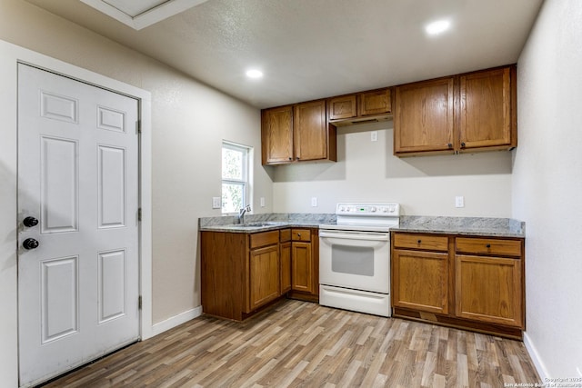 kitchen featuring light stone countertops, light wood-style flooring, a sink, white electric range, and brown cabinets