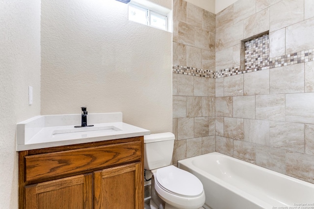 full bathroom featuring toilet, vanity, and a textured wall