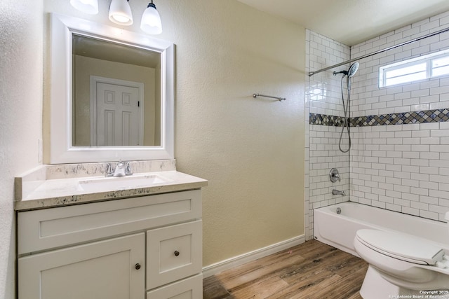 full bath with toilet, shower / washtub combination, wood finished floors, baseboards, and vanity