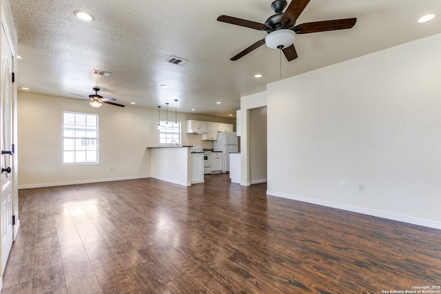 unfurnished living room featuring visible vents, baseboards, a textured ceiling, and dark wood finished floors