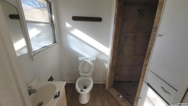 full bathroom with wood finished floors, baseboards, a sink, a shower stall, and toilet