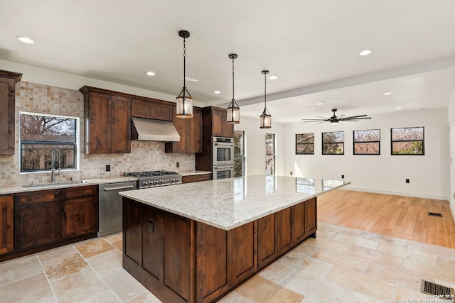 kitchen featuring backsplash, extractor fan, plenty of natural light, stainless steel appliances, and a sink