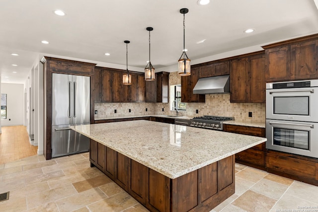 kitchen featuring a kitchen island, appliances with stainless steel finishes, exhaust hood, stone tile flooring, and a sink