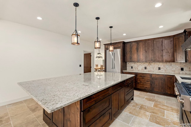 kitchen with light stone countertops, a kitchen island, recessed lighting, premium appliances, and tasteful backsplash