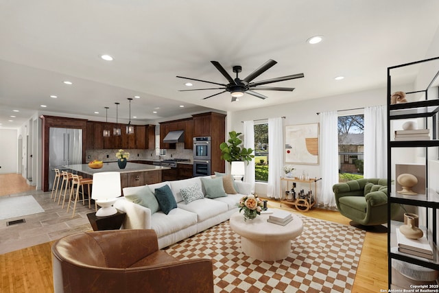 living area with recessed lighting, visible vents, a ceiling fan, and light wood finished floors