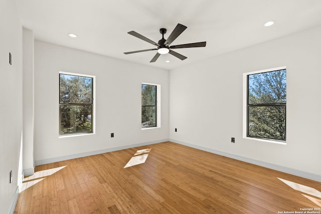 spare room featuring light wood finished floors, recessed lighting, a healthy amount of sunlight, and baseboards