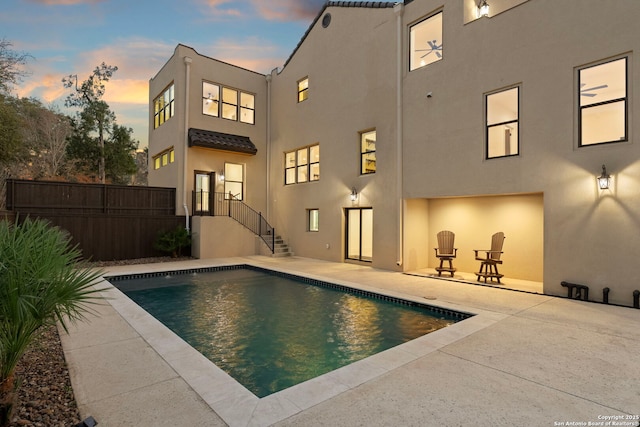 rear view of property with a patio, fence, a fenced in pool, and stucco siding