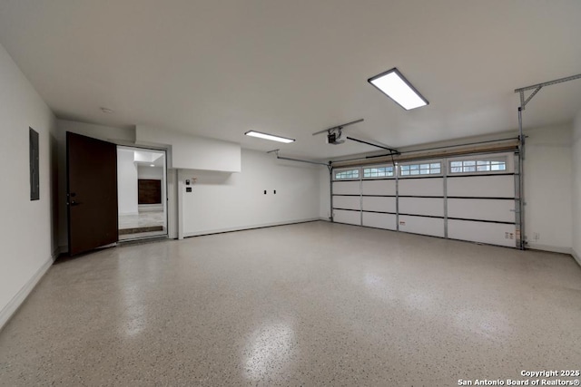 garage featuring electric panel, a garage door opener, and baseboards