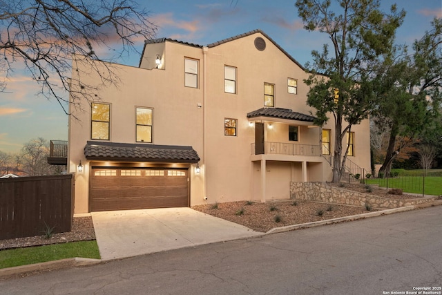 mediterranean / spanish house with a tiled roof, stucco siding, driveway, and a garage