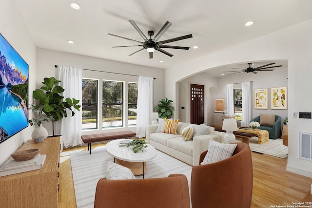 living room with visible vents, light wood finished floors, recessed lighting, arched walkways, and ceiling fan