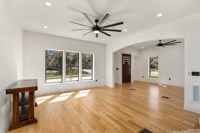 unfurnished living room featuring visible vents, light wood-style flooring, recessed lighting, arched walkways, and ceiling fan