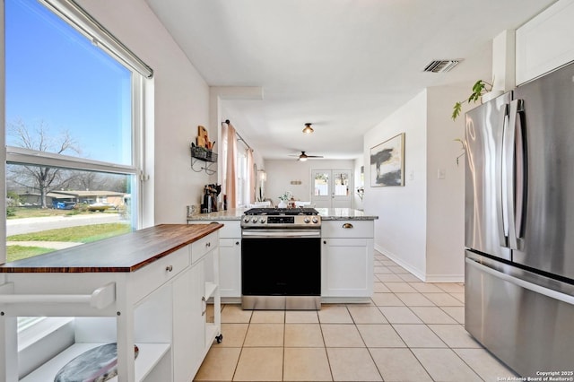 kitchen featuring light tile patterned floors, visible vents, a peninsula, stainless steel appliances, and white cabinetry