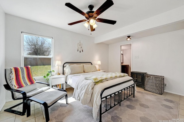 bedroom featuring baseboards, a ceiling fan, and a wood stove