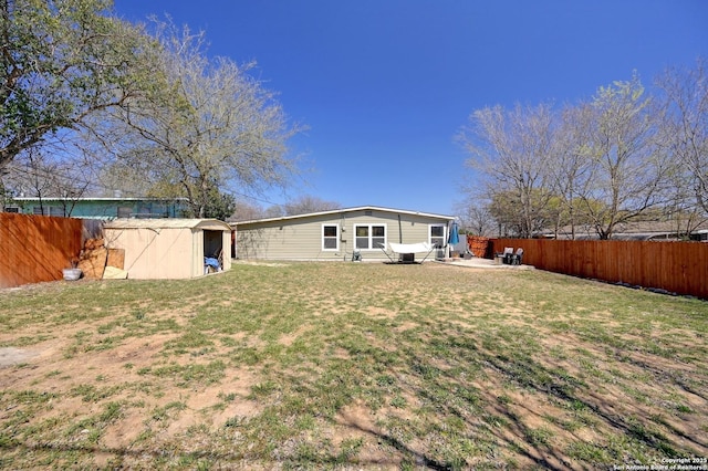 rear view of house with an outdoor structure, a yard, a fenced backyard, and a patio area