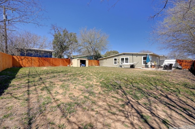 view of yard with an outdoor structure, a fenced backyard, and a patio