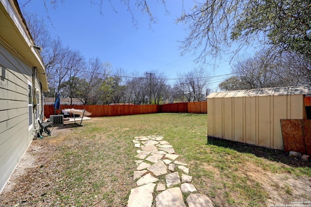 view of yard with a storage unit, an outdoor structure, central AC unit, and a fenced backyard