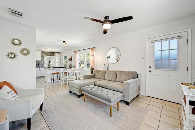 living area featuring light tile patterned floors, visible vents, and ceiling fan