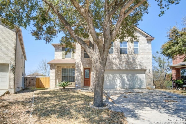 traditional home featuring a gate, fence, concrete driveway, an attached garage, and brick siding