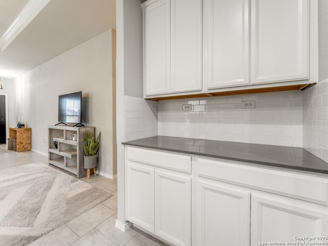 kitchen with dark countertops, light tile patterned floors, backsplash, and white cabinetry