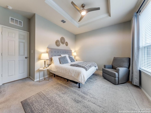 carpeted bedroom with visible vents, a raised ceiling, and baseboards